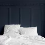 Lit avec oreiller et couette blanc avec un mur bleu marine